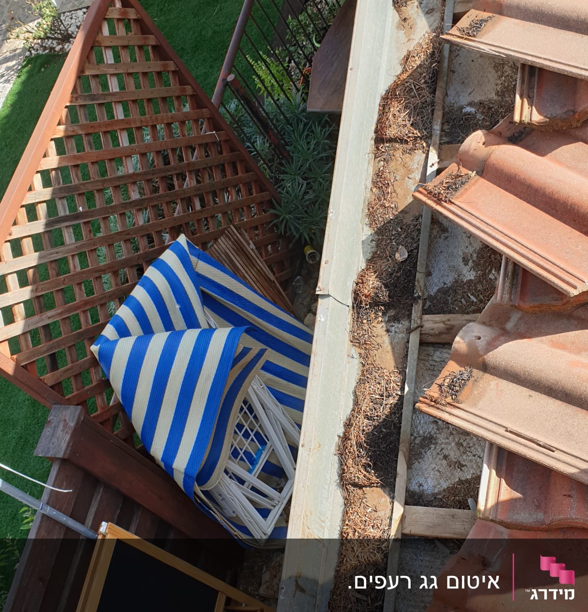 רעפים חומים על גג עם עלים יבשים בתעלה